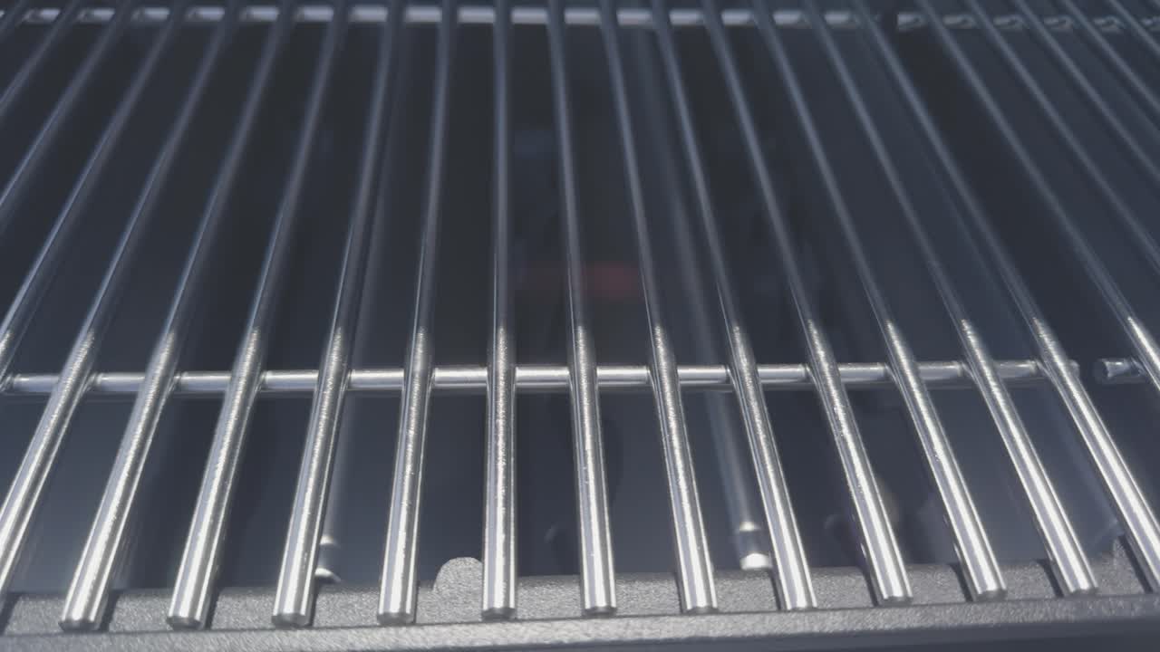 Camera slides from left to right over brand new stainless steel bbq grates. The heat is on and the grill is ready!