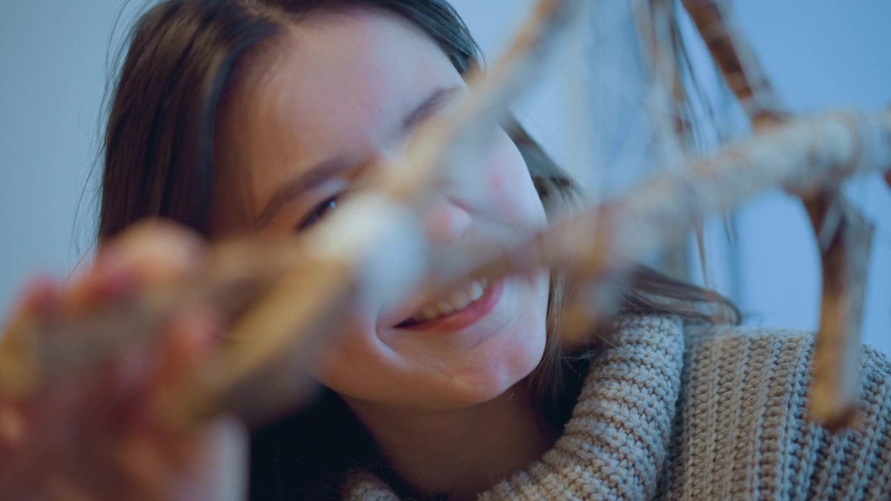 Close up of woman carefully arranging twigs and string to create intricate natural sculpture. focus remains on her hands manipulating materials highlighting detailed interaction with organic