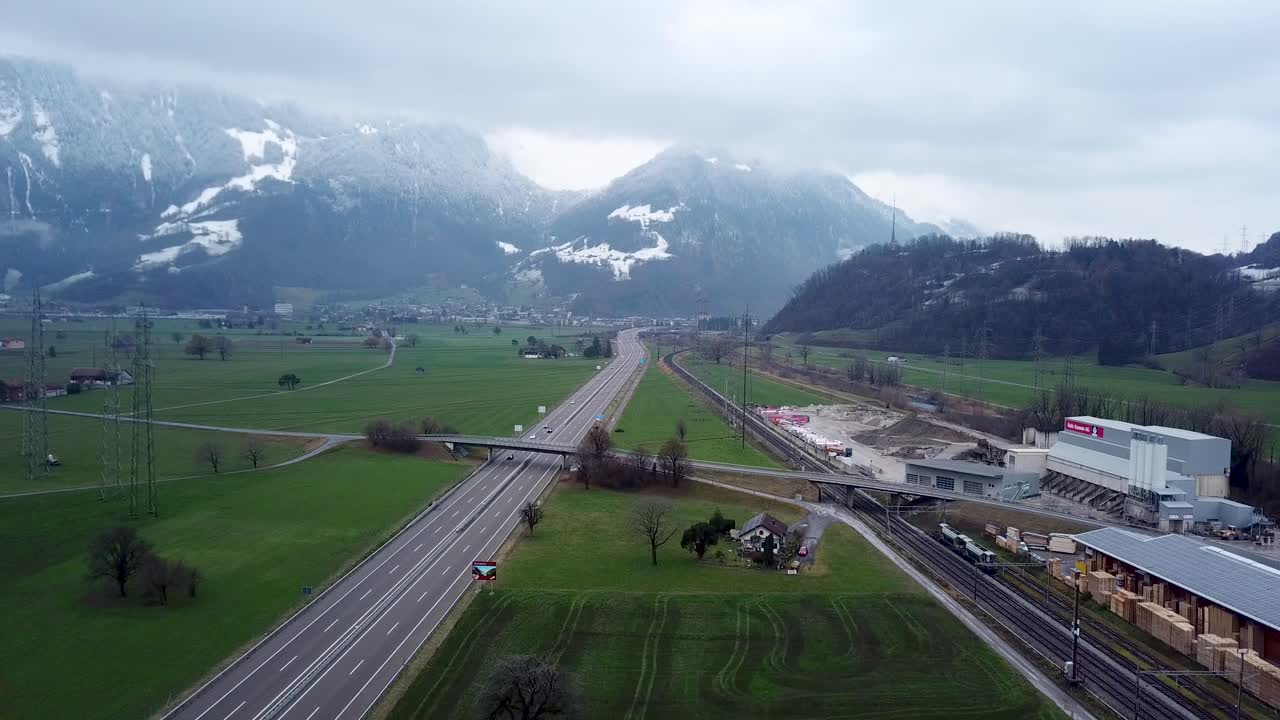 고속도로는 배경에 산맥이 있는 녹색 들판을 통과합니다.