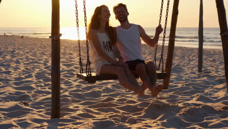 couple enjoying a sunset swing on the beach
