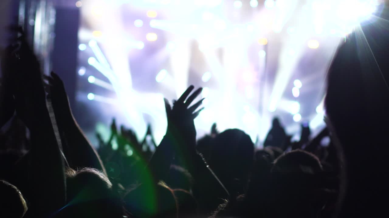 manos abstractas en el aire aplaudiendo. fuera de foco luces del escenario en el fondo