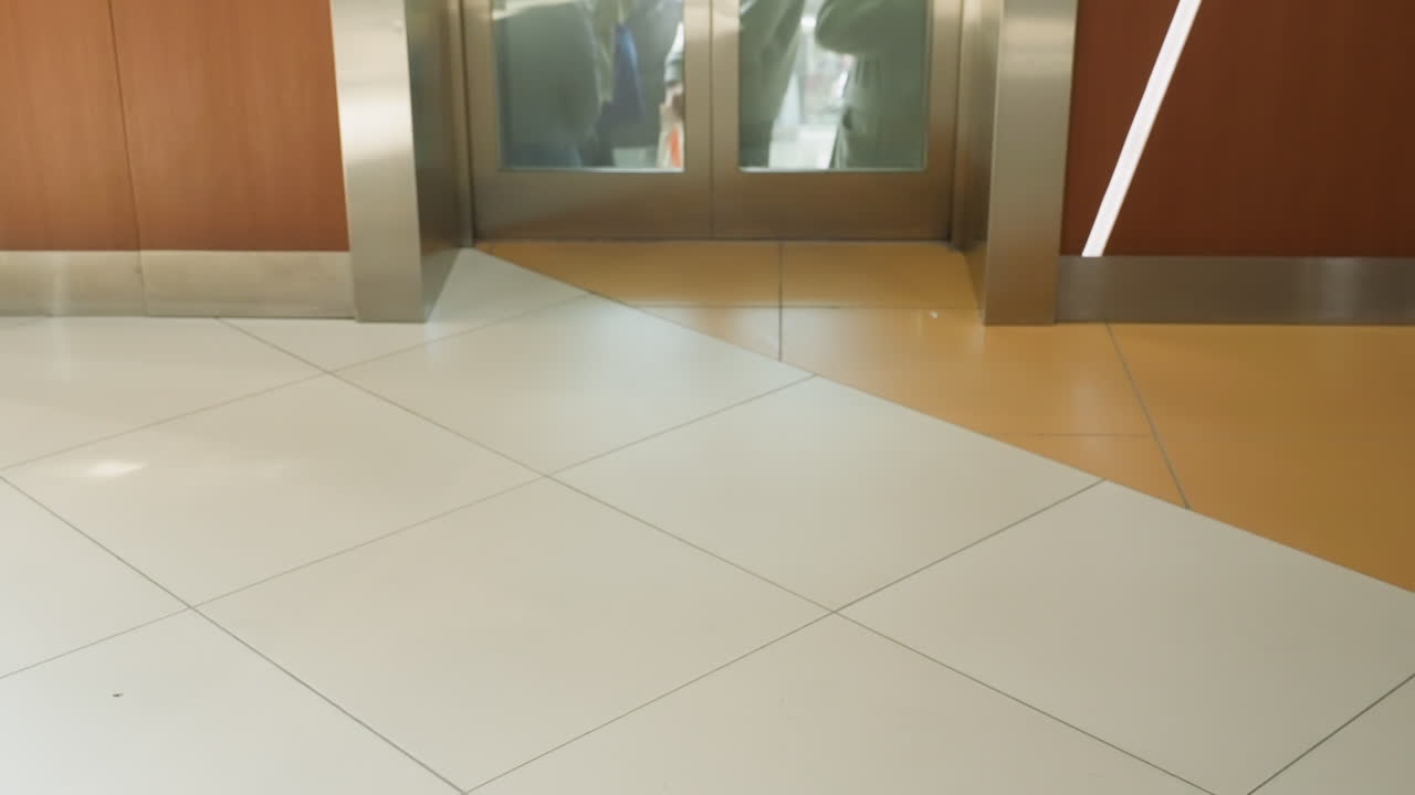 una vista detallada en primera persona tomada con una cámara de mano, capturando las mitades inferiores de varias personas de pie dentro de un ascensor. la imagen se centra en la diversidad de calzado y ropa