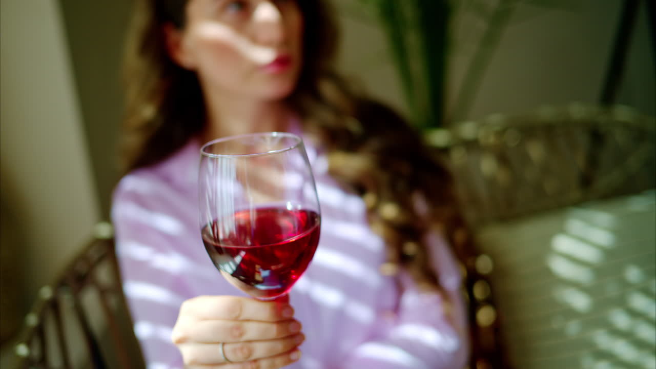 Donna che fa roteare un bicchiere di vino rosso alla luce del giorno
