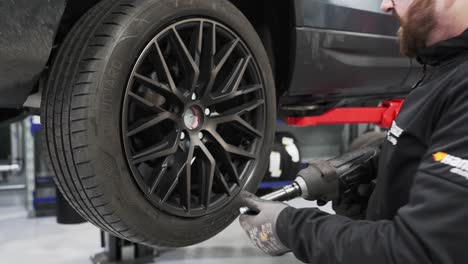 A-mechanic-diligently-servicing-a-car,-expertly-fixing-a-tire-in-a-well-equipped-mechanic-garage-shop