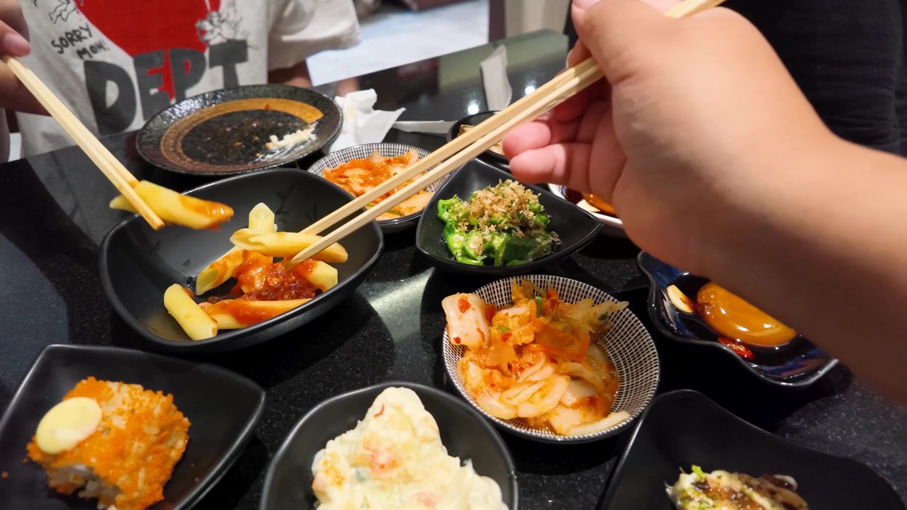Close-up de mãos usando hashis de madeira para pegar macarrão em um restaurante em Banguecoque