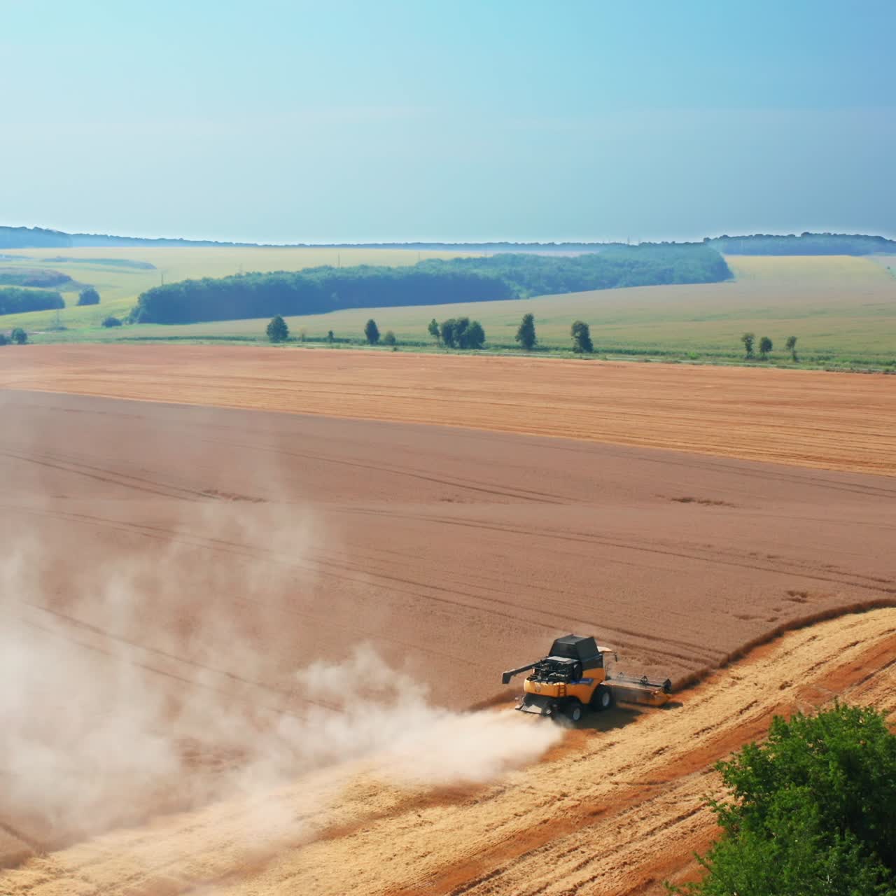 Yellow harvester combine mows the field of wheat. Another machine standing not far away. Top view. Nature backdrop