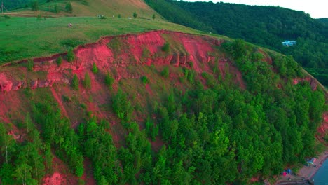 a small village at the foot of the hill, which is covered with thick greenery. extraordinarily beautiful red soil on the hillside. the concept of a family holiday.