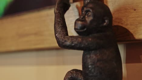 black colored statue of a monkey, zoom in cinematic footage with wooden background