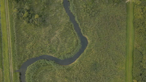 top down aerial view of winding curvy river through flat green beautiful farmland