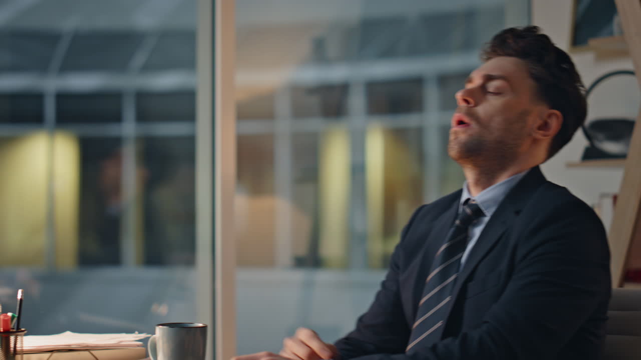 Frustrated professional holding head sitting dark office showing stress closeup