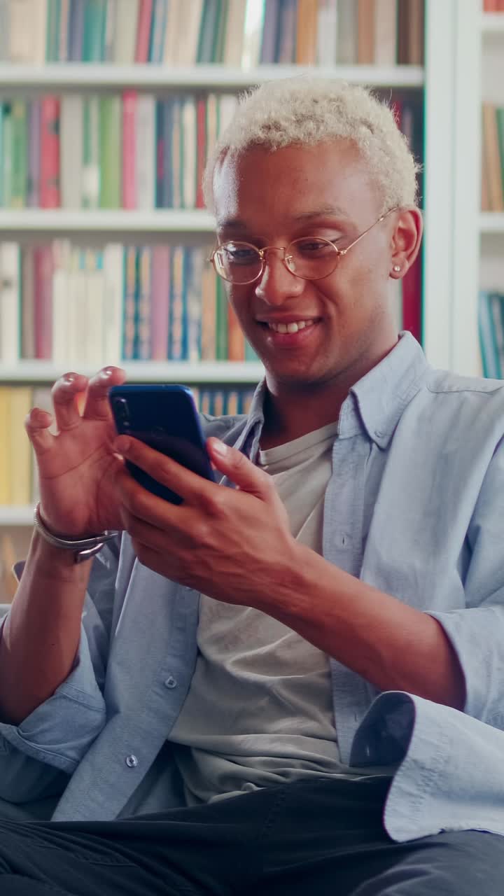 Young joy african american man holding mobile phone in hands pressing screen