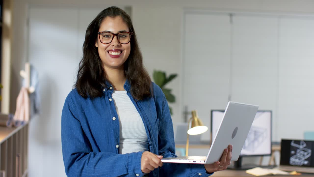 Žena posouvá notebook do pravé ruky, odhaluje obrazovku a usmívá se, prezentuje 3D model ve studiu