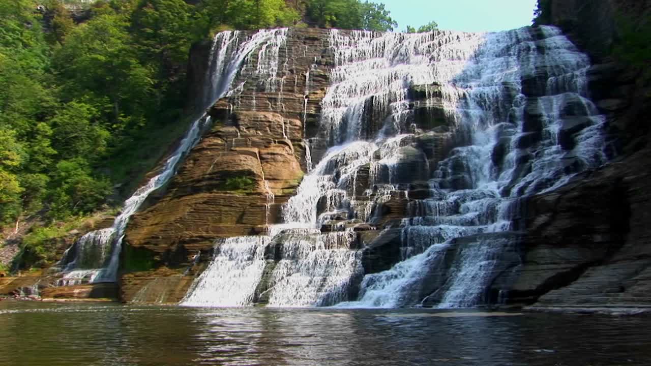 una amplia cascada fluye sobre salientes rocosos en ithaca falls nueva york