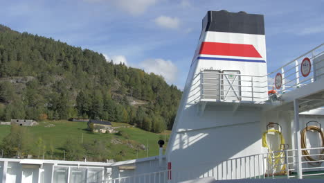 view from a norwegian ferry passing by a lush green mountainside on a sunny day, static