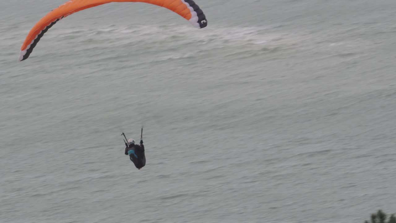 A man on a paraglider flying at high speed above sea level