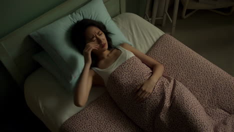 woman lying in bed experiencing stomach pain and distress