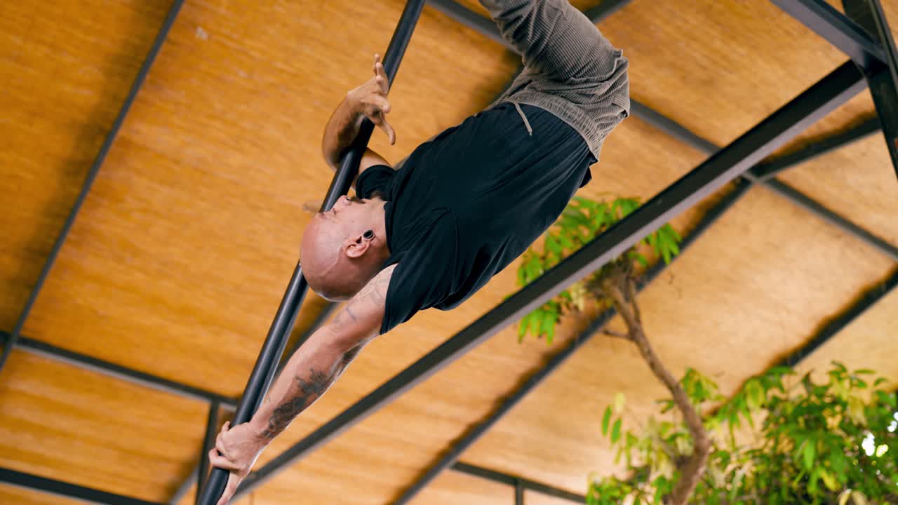Mann utfører calisthenics-øvelse på en turnstang opp ned.