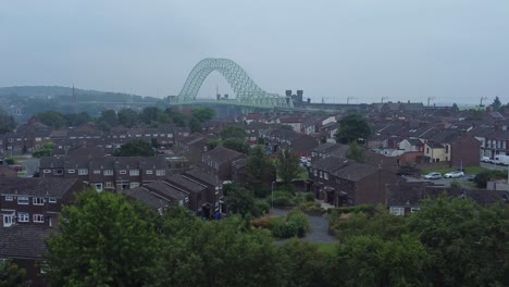 puente de runcorn del norte británico suburbano residencial casa adosada vecindario vista aérea derecha inversa sobre la línea de árboles