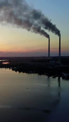 smoke from the pipe factory near the river. landscape of an industrial estate with pipe factory smoke near river vertical video