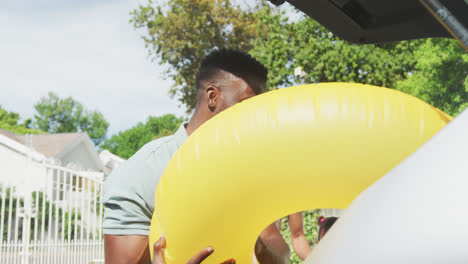 happy african american family packing car with beach items on holiday