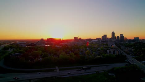 golden hour aerial of indianapolis skyline with sun behind skyscrapers and semi truck drivers on highway perfect for cityscape and transportation projects.