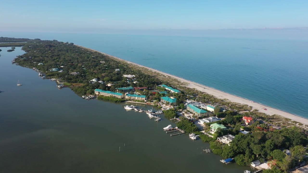 Droneoptagelse af Tween Waters Inn og Marina, der strækker sig over begge sider af Captiva Island — både og marina på bugtsiden på den ene side, sandet kystlinje ud til Den Mexicanske Golf på den anden.