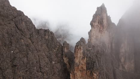 steep rock face with clouds and snow in the mountains, dolomites, italy, europe, drone