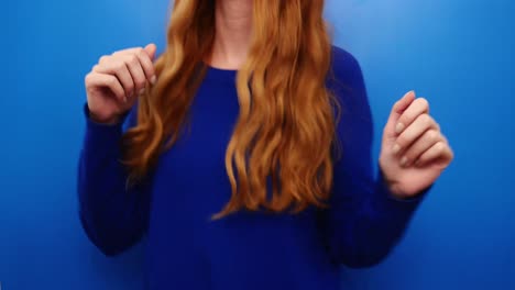 cheerful ginger redhead young girl wearing blue sweater dancing isolated on blue color background in studio