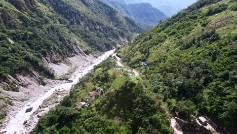 remote village buildings and dirt road along kali gandaki gorge, kali gandaki river, flying towards rupse falls in central nepal - aerial flyover