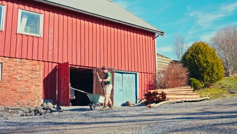 a man is transferring poles from the storage area to the wheelbarrow to be charred for preservation - static shot