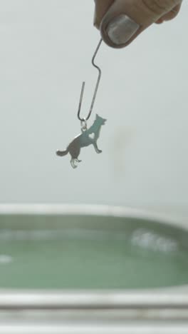 cleaning a silver dog charm in liquid