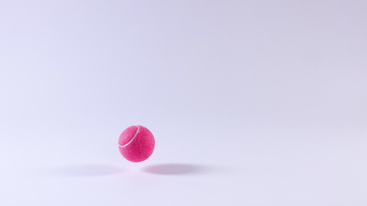 una pelota de tenis rosa rebotando en una superficie blanca