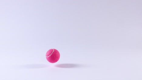 pink tennis ball bouncing on a white surface