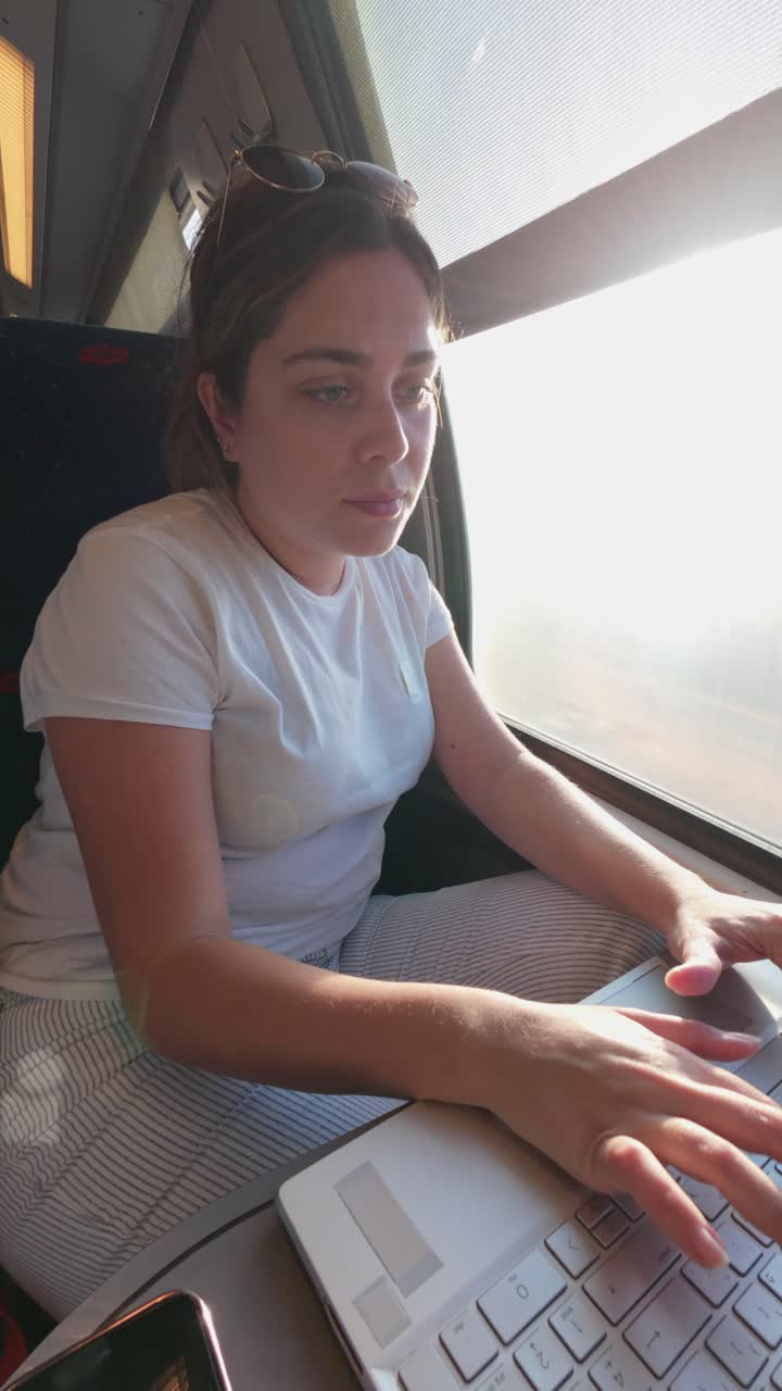 Female Freelancer Typing on Laptop Keyboard on a Moving Train