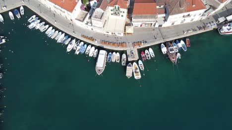 Barcos-De-Pesca-Alineados-Amarrados-A-Los-Muelles-Del-Puerto-De-La-Ciudad-De-Milna-Contra-Casas-De-Piedra-Caliza-Blanca,-Isla-De-Brac