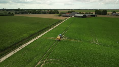 Fliegen-Auf-Und-über-Einen-Traktor-Mit-Einer-Anhängespritze,-Die-Pflanzenschutzmittel-Versprüht