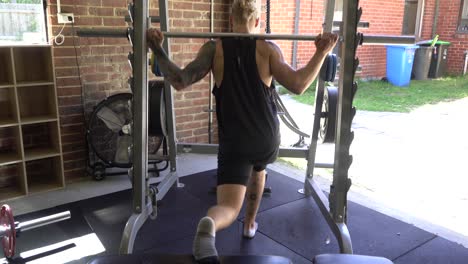 tattoo man muscles in home gym back leg raise smith machine lunge