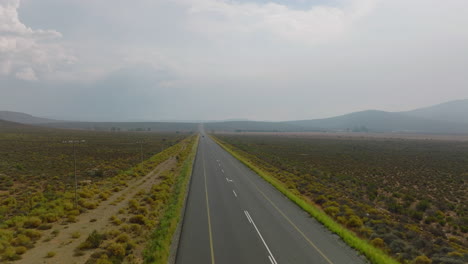 Landungsaufnahmen-Der-Straße-In-Flacher-Landschaft.-LKW-Mit-Auflieger-Fährt-Weg.-Stromleitungen-Parallel-Zur-Straße.-Südafrika