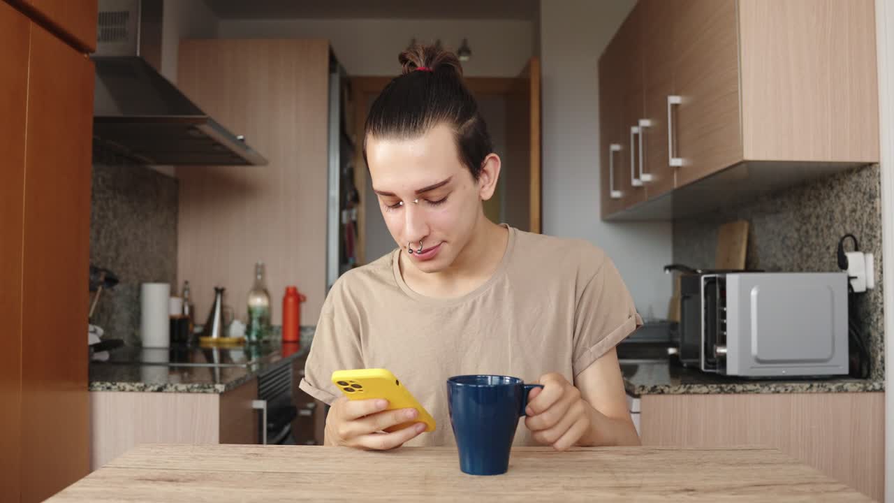 A person using their phone in a kitchen while drinking coffee