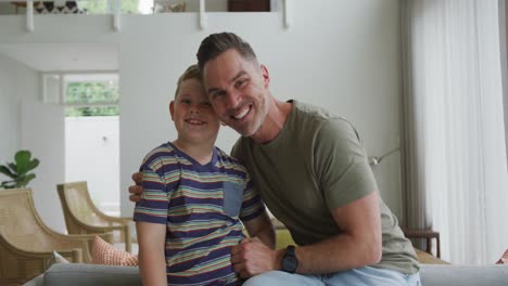 retrato de padre y hijo caucásicos sonriendo en la sala de estar en casa