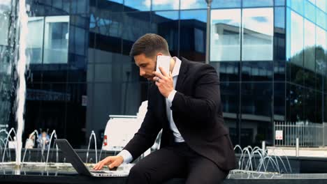 businessman using laptop while talking on phone