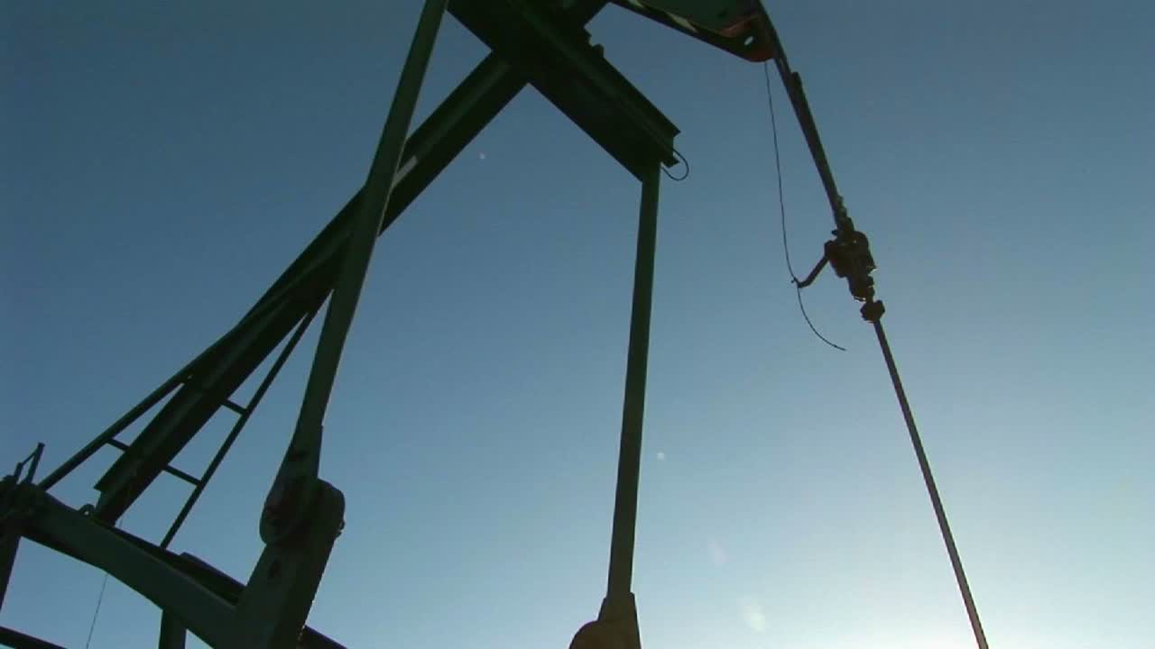 푸른 하늘을 배경으로 펌프 잭이 실루엣으로 그려져 있습니다.