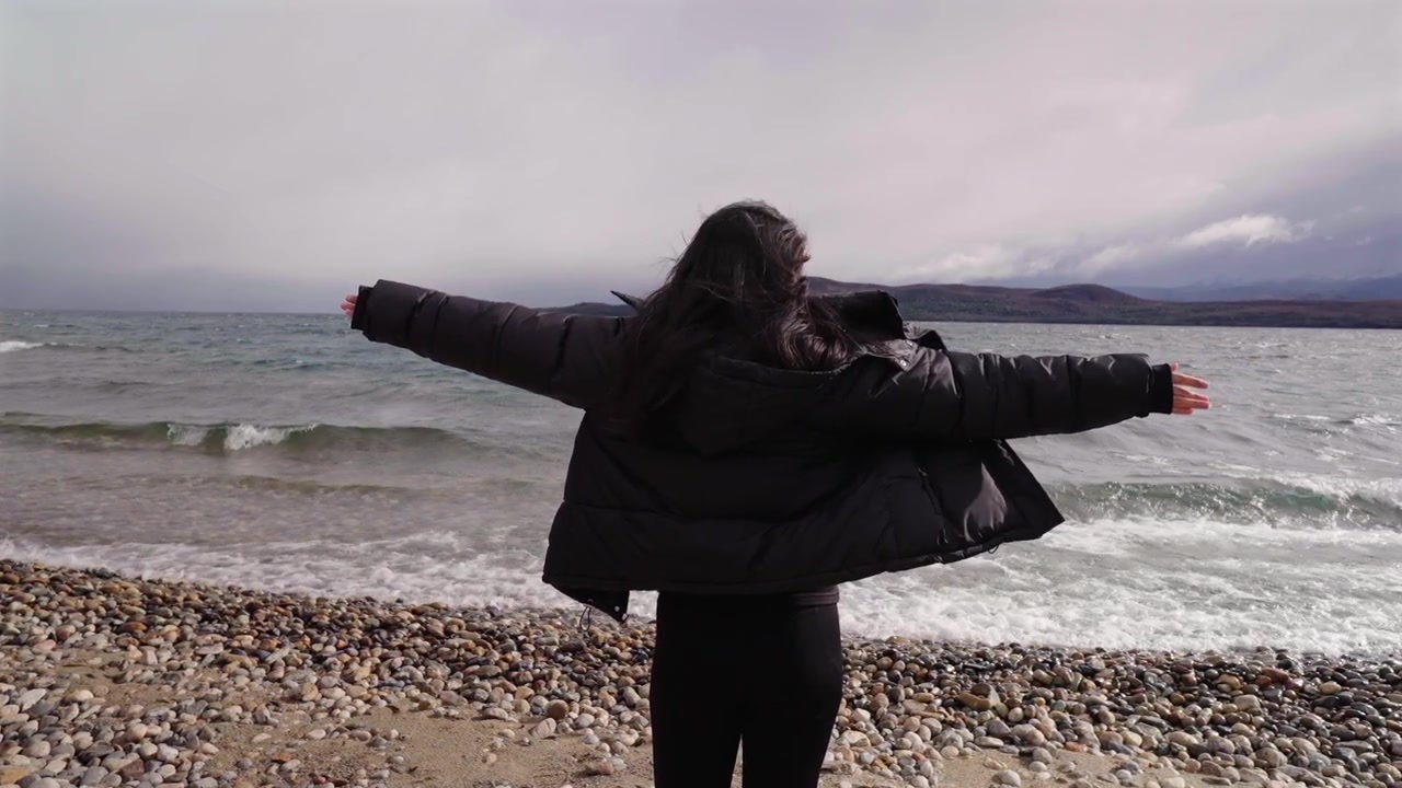 Donna a braccia aperte sulla riva del Lago Nahuel Huapi in Rio Negro, Argentina.