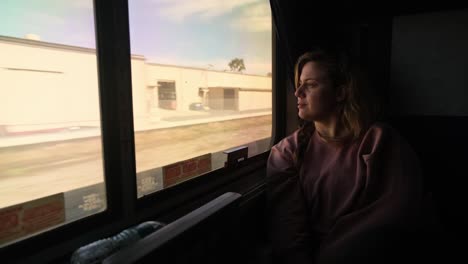 mujer en el tren mira pacíficamente por la ventana mientras el terreno avanza