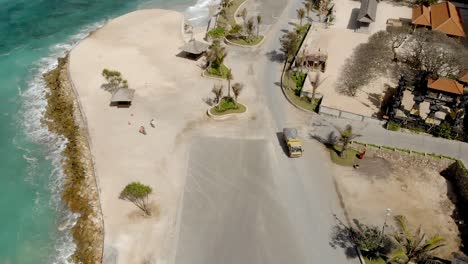 yellow lorry drive seaside street at melasti beach, bali, indonesia, aerial view