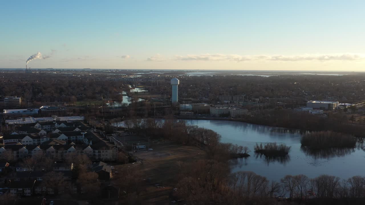 una vista aérea de un barrio suburbano en long island justo antes del atardecer, lo suficientemente alto como para ver el horizonte y un lago congelado