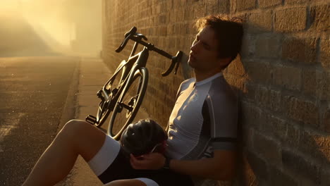 cyclist resting against a brick wall at golden hour