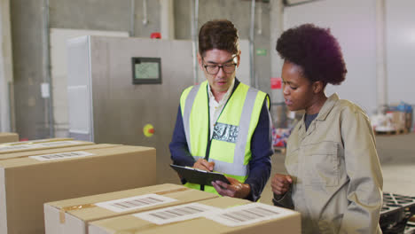 diverse male and female workers with clipboard and boxes in warehouse