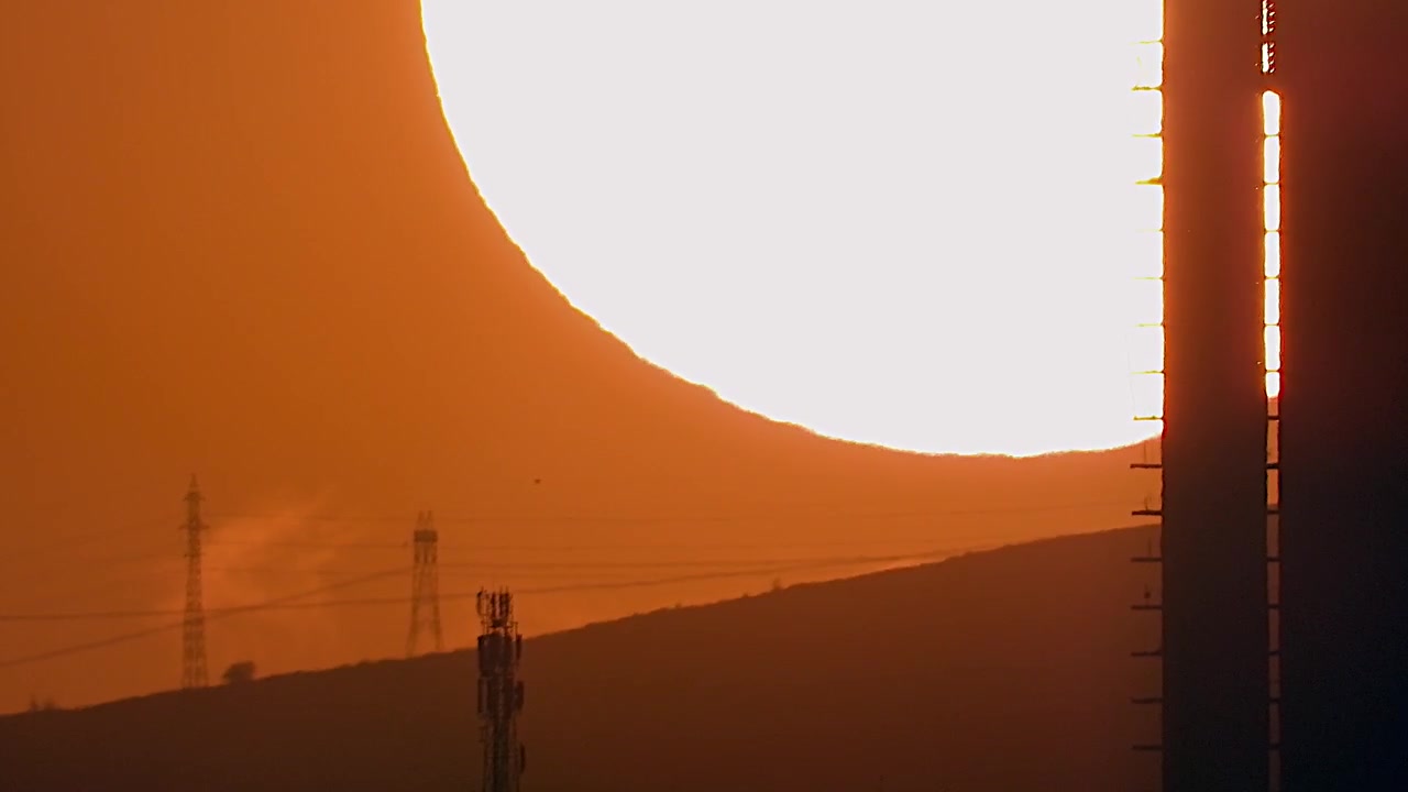 Large Sun Setting Behind a Hill and Construction Structure