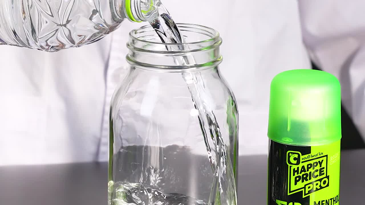 실험실 코트를 입은 사람이 용기에 액체를 부어 화학 반응 실험을 시연합니다.